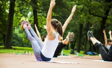 Outdoor yoga session in the park with group stretching.
