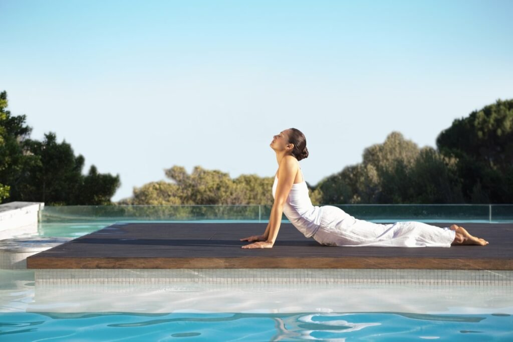 Woman practicing yoga by the pool at Wellness Privé Portugal.