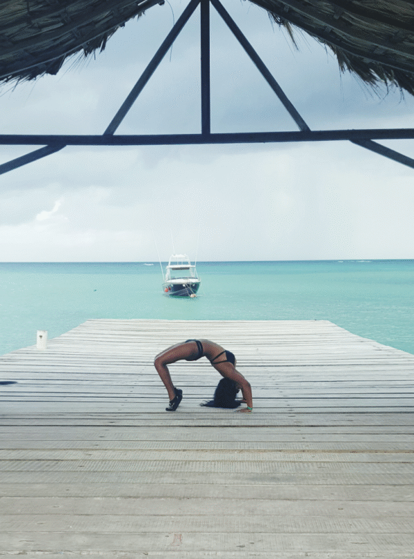Guest practicing yoga bridge pose on ocean deck.