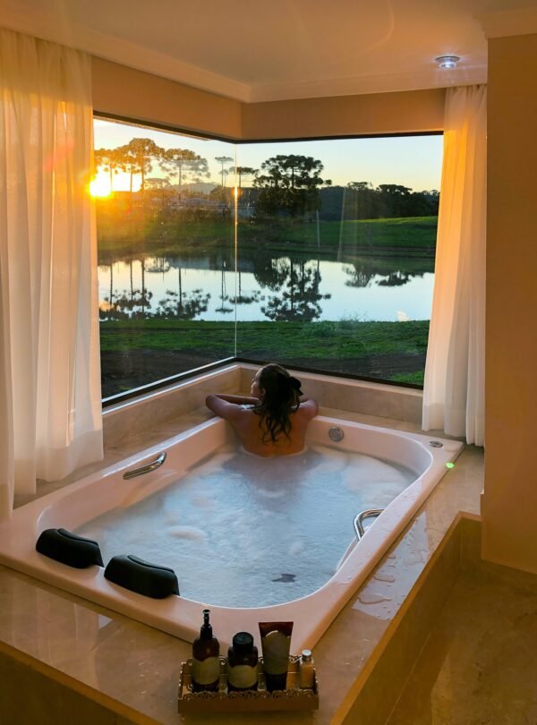 Woman relaxing in jacuzzi bathtub with sunset view.