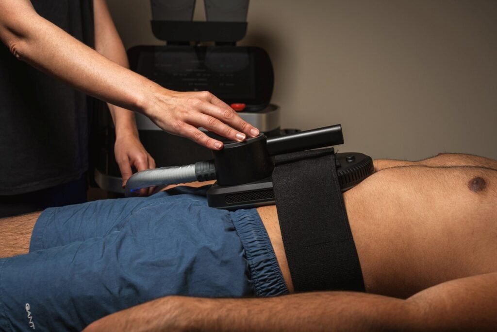 Therapist performing body treatment with equipment at wellness retreat.