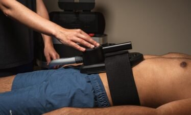 Therapist performing body treatment with equipment at wellness retreat.