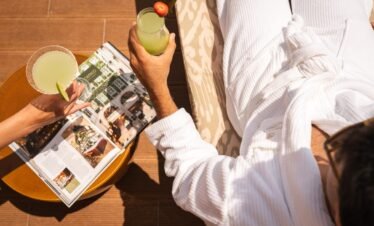 Guest relaxing with fresh juice and magazine at the sea-view balcony for stress-relief