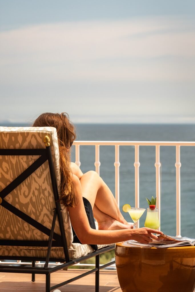 Guest enjoying ocean-view balcony with drink at Wellness Privé.